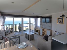 A living room with a sofa, table, and television at 619 Chy-An-Mor in Perranporth