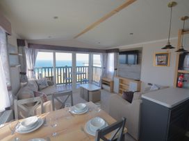 A living room with a sofa and dining area at 619 Chy-An-Mor in Perranporth