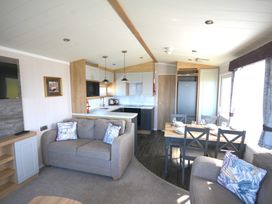 A living room with a sofa and dining area at 619 Chy-An-Mor in Perranporth