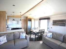A living room with a sofa and dining area at 619 Chy-An-Mor in Perranporth