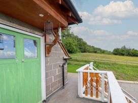 A view of an exterior area with a green door and bird feeders at Hay Loft at Ebenezer Chapel Milwr