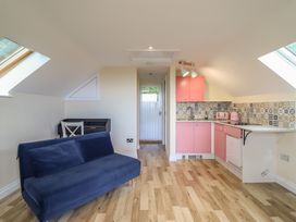 A kitchen area with a sofa and pink cabinets at Hay Loft at Ebenezer Chapel in Milwr