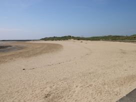 A beach with sand and water at Twyni Bach