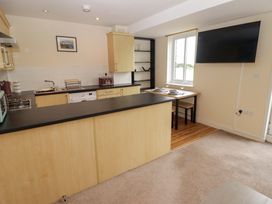 A kitchen with a dining table and television at Twyni Bach