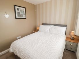 A bedroom with a bed, bedside table, lamp, and picture frame at Twyni Bach