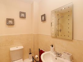 A bathroom with a toilet, sink, shower, and mirror at Twyni Bach