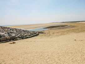 A beach with sand and rocks near water at Twyni Bach