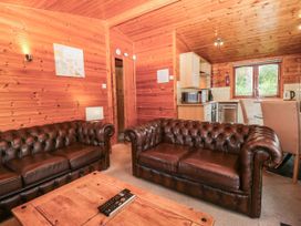A living room with brown sofas and a kitchenette at 89 Ambleside in White Cross Bay