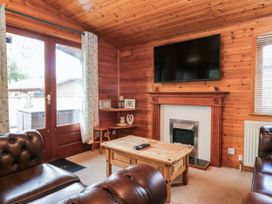 A living room with a television above a fireplace at 89 Ambleside in White Cross Bay