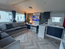 A living room with a sofa and television at Presthaven - Denbigh Dunes, Gronant