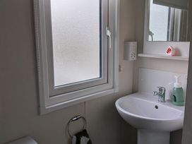 A bathroom with a sink and mirror at Presthaven - Denbigh Dunes, Gronant