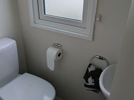 A bathroom with a toilet and window at Presthaven - Denbigh Dunes in Gronant