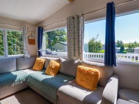 A living room with a sofa and large windows at Porthcurno 5 Perranwell near Goonhavern