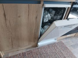 A kitchen with an open dishwasher containing dishes in Porthcurno 5, Perranwell near Goonhavern