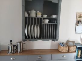 A kitchen cupboard with plates and kitchenware at Porthcurno 5 Perranwell near Goonhavern