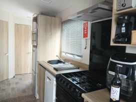 A kitchen with a sink, stove, and refrigerator at Porthcurno 5 Perranwell near Goonhavern