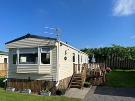 A caravan with a wooden deck and garden area at Hornshole Hideaway Caravan Hawick Riverside Caravan Park near Hawick