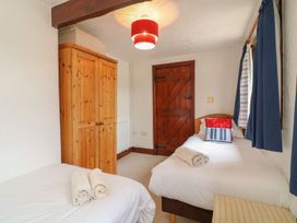 A bedroom with two beds and a wardrobe at Pillhead Cart Linhay in Bideford