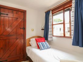 A bedroom with a bed and wooden door at Pillhead Cart Linhay in Bideford