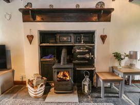 A living room with a wood stove and wooden shelves at Brigg House in Broughton-in-Furness