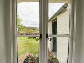 A view from a window showing a garden with flowers and a stone pathway at Brigg House Broughton-in-Furness