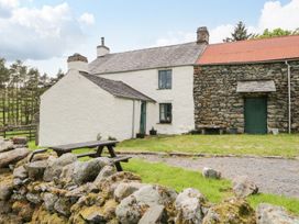 A cottage with a stone wall and a table at Brigg House in Broughton-in-Furness