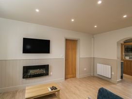 A living room with a television above a fireplace and a coffee table at Foxglove in Stratton Audley near Bicester