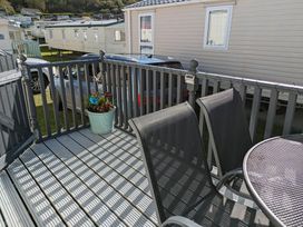 An outdoor deck with a table and chairs at Clarach Bay Holiday Village W18 Aberystwyth