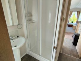 A bathroom with a shower and sink at Clarach Bay Holiday Village W18 Aberystwyth