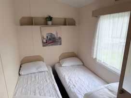 A bedroom with two beds and a picture on the wall at Holiday Park Seawick Clacton-on-Sea