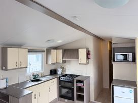 A kitchen with cabinets, stove and sink at Holiday Park Seawick in Clacton-on-Sea