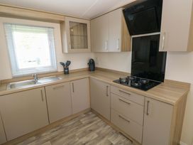 A kitchen with a sink, gas stove, and cabinets at Sandpiper in Narberth