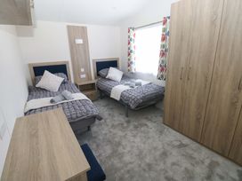 A bedroom with two beds and a wardrobe at Sandpiper Narberth