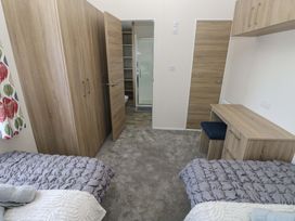 A bedroom with two beds and a wardrobe at Sandpiper in Narberth