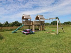A playground with a slide and swings in an outdoor area at Sandpiper in Narberth