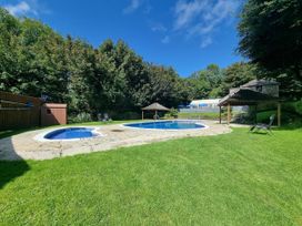 A swimming pool and hot tub surrounded by grass and trees in a garden