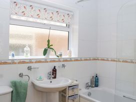 A bathroom with a sink, bath, and window at Halsdon Avenue in Exmouth