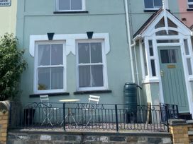 A table and chairs outside a house with a green door at Arosfa in New Quay