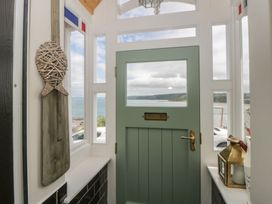 A hallway with a green door and windows overlooking the sea at Arosfa New Quay