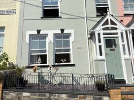 An outdoor area with a table and chair in front of a house at Arosfa in New Quay