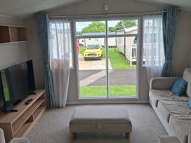 A living room with a television and sofa at Primrose Valley, Amara's Retreat in Filey