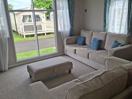A living room with a sofa and footstool at Primrose Valley, Amara's Retreat in Filey