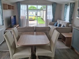 A living room with a dining area and a view outside at Primrose Valley, Amara's Retreat, Filey
