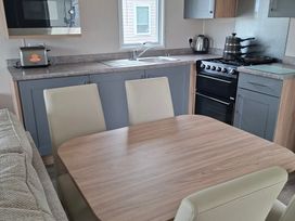 A kitchen with appliances and dining table at Primrose Valley, Amara's Retreat, Filey