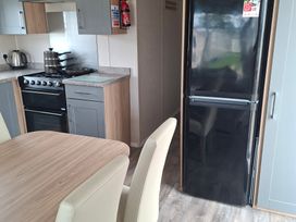 A kitchen with a stovetop and black fridge at Primrose Valley, Amara's Retreat in Filey