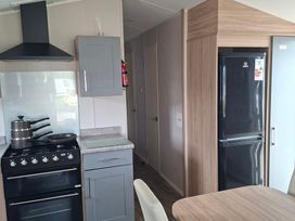 A kitchen with stove and refrigerator at Primrose Valley, Amara's Retreat in Filey