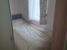 A bedroom with a bed and window at Primrose Valley, Amara's Retreat in Filey