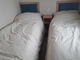 A bedroom with twin beds and a bedside table at Primrose Valley, Amara's Retreat in Filey