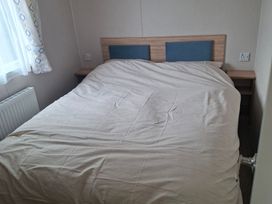 A bedroom with a bed and bedside table at Primrose Valley, Amara's Retreat in Filey