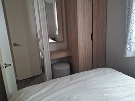 A bedroom with a bed and wardrobe at Primrose Valley, Amara's Retreat in Filey